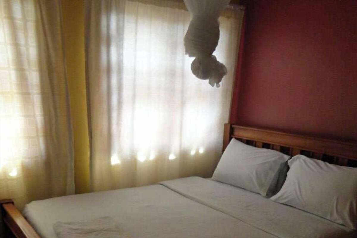 Ein Bett mit weißer Bettwäsche, einem hölzernen Kopfteil und einem Nachttisch mit einem Buch.
