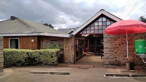 Un edificio con fachada de madera, muros de piedra y un paraguas rojo, identificado como 'Hills Country Lodge'.