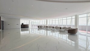 A spacious lobby with a polished marble floor, a reception desk, and a seating area with sofas and tables.
