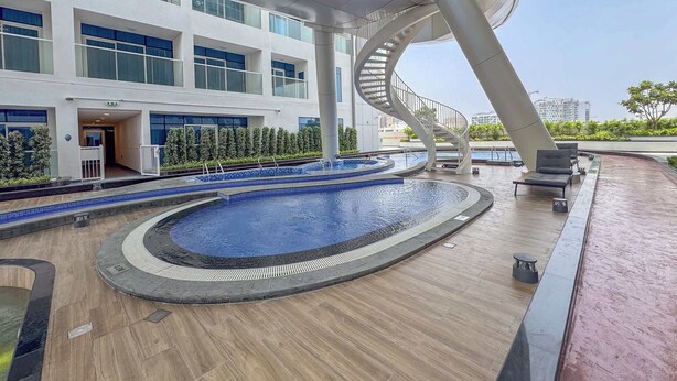 A modern building with a pool area, including a spiral staircase and lounge chairs.