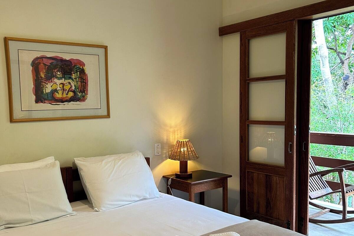 Une chambre d’hôtel avec un lit, une table de chevet avec une lampe, une porte en bois et un tableau encadré au mur.