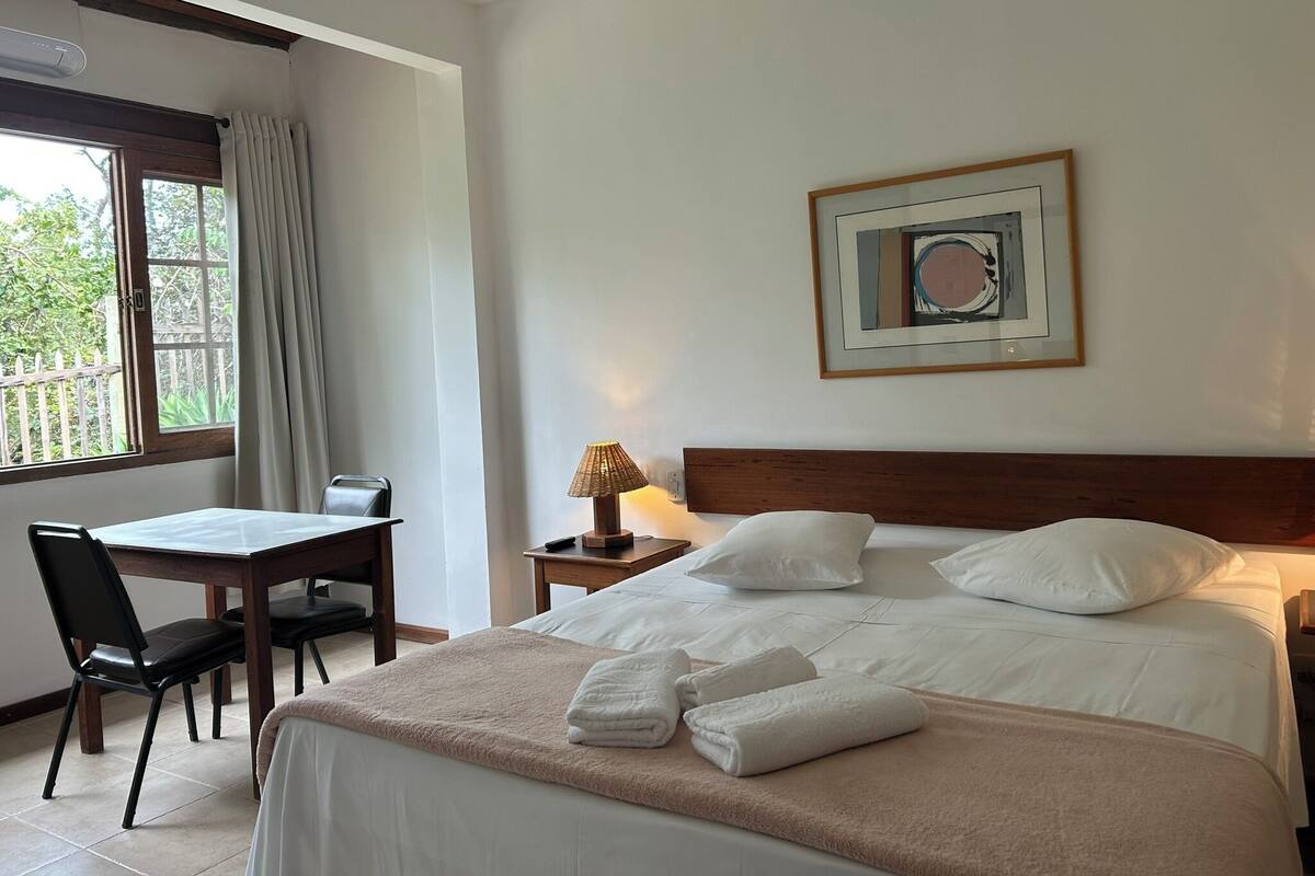 Une chambre d’hôtel avec un lit, un bureau, une chaise et une fenêtre avec des rideaux.