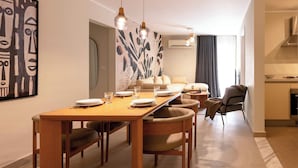 Una sala de estar moderna con comedor, que incluye una mesa de madera, asientos cómodos y un cuadro abstracto grande en la pared.