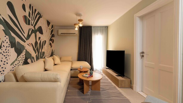 Una sala de estar moderna con un sofá, una mesa de centro, un televisor y una pared con diseño.