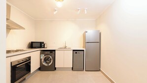 Cocina compacta con microondas, horno, lavadora, lavavajillas y refrigerador.