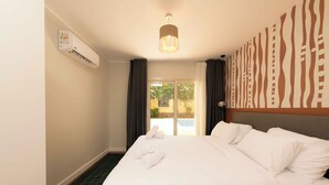 Habitación de hotel con una cama, aire acondicionado de pared, lámpara en el techo y vistas al exterior a través de una puerta de cristal.