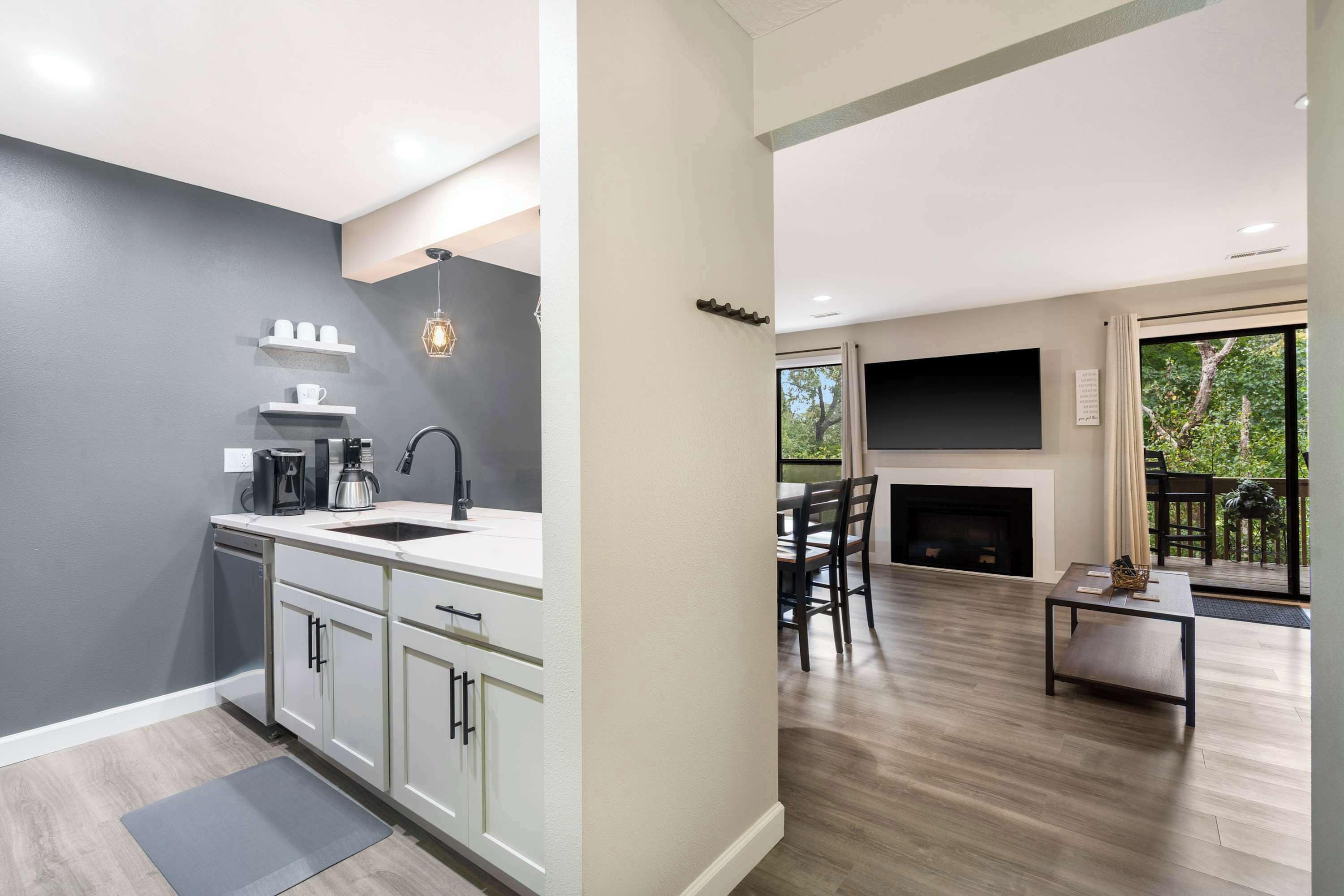 A modern kitchen with white cabinets, a built-in dishwasher, and a coffee maker.