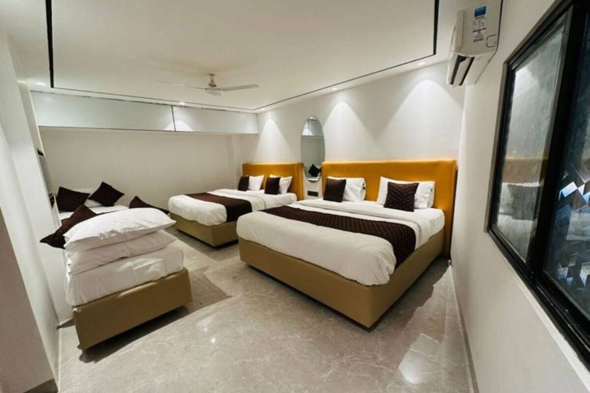 A hotel room with two beds, a ceiling fan, a window, and a wall-mounted air conditioning unit.