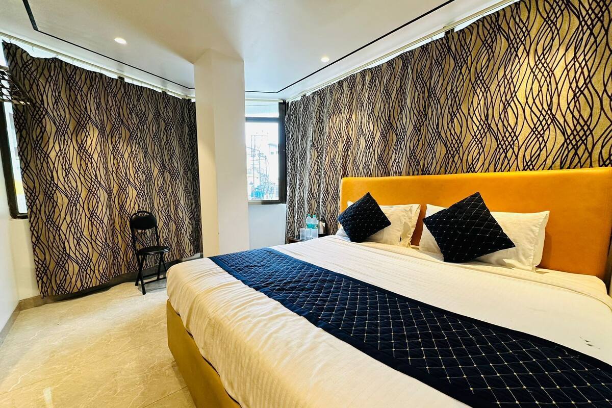 A modern hotel room with a large bed, a chair, and patterned walls.