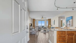 A spacious living area with a view of the city, a kitchen with wooden cabinets, and a dining area with a round table and chairs.