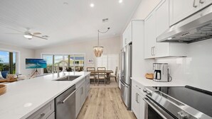 Une cuisine moderne avec des meubles blancs, des appareils en acier inoxydable et un plancher en bois.