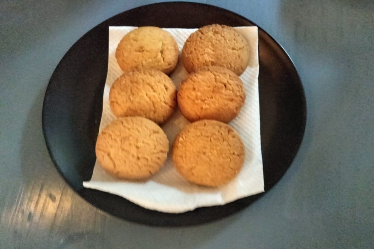 Un plato con seis galletas sobre un fondo oscuro.