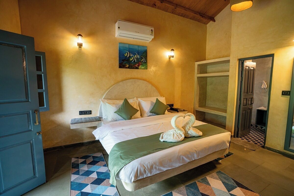 Una camera d'albergo con un letto, due luci fissate al muro, un condizionatore d'aria e un quadro con dei pesci.