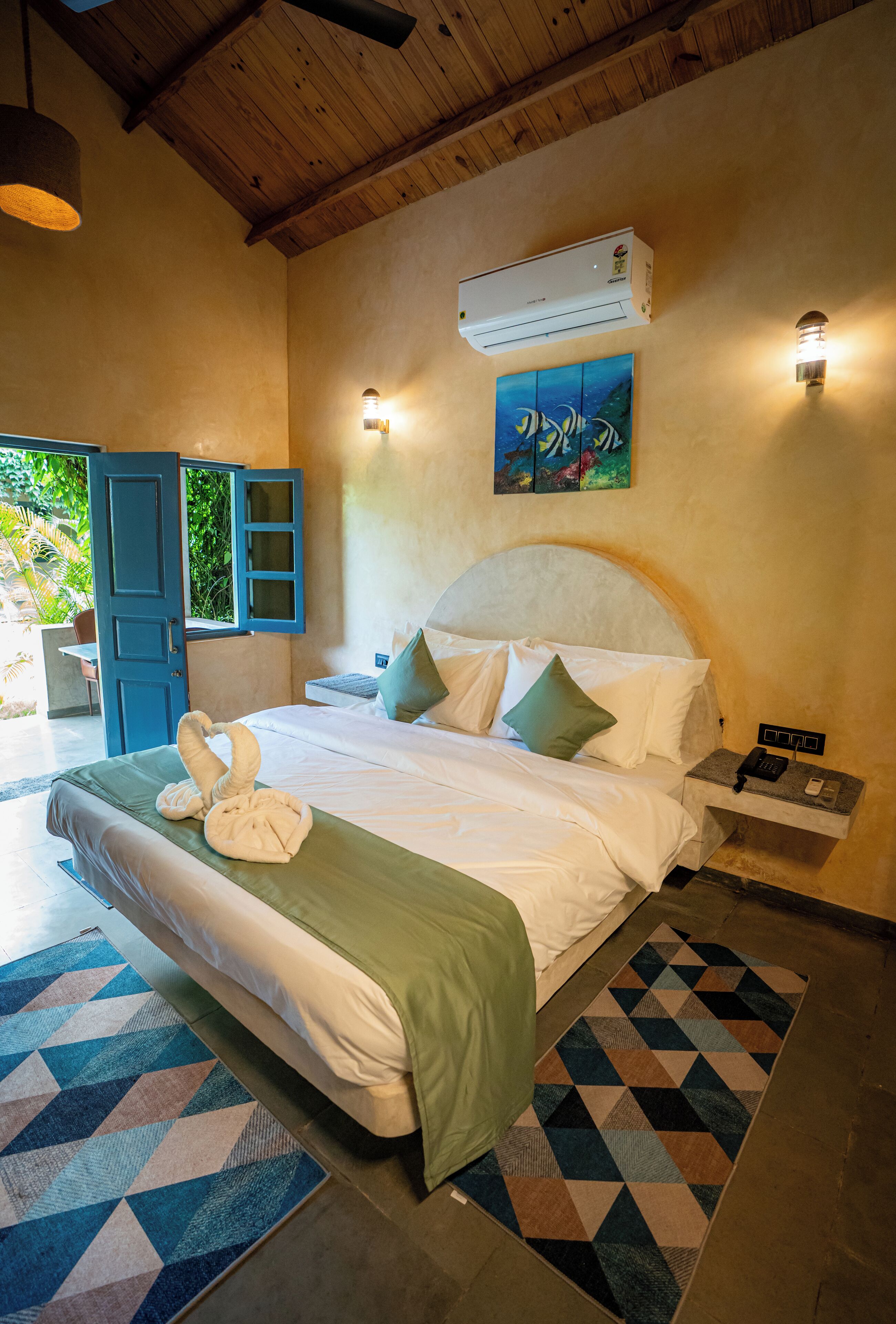A bedroom with a bed, a nightstand, an air conditioning unit, and a painting on the wall.