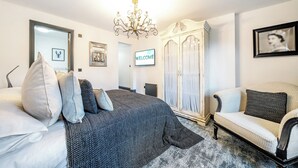 A bedroom with a bed, a chair, a wardrobe, a chandelier, and a 'WELCOME' sign. - The Stables (Poulton-le-Fylde)