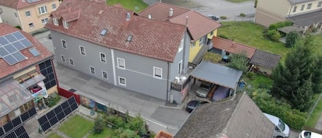 Zona residencial con un edificio de dos pisos, un estacionamiento y una estructura comercial pequeña con techo azul.