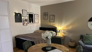 Quarto com cama, mesa de cabeceira, abajur e obra de arte na parede.