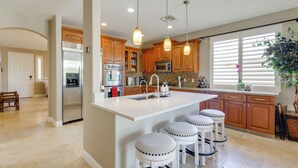 A modern kitchen with wooden cabinets, stainless steel appliances, and a central island with bar stools. - Private Yard & Fairway View: Phoenix Golf Retreat! (Phoenix)