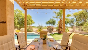 A covered outdoor dining area with a pool view, two chairs, a table with plates and glasses, and a potted plant. - Private Yard & Fairway View: Phoenix Golf Retreat! (Phoenix)