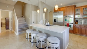 A modern kitchen with a central island, bar stools, stainless steel appliances, wooden cabinets, and pendant lighting. - Private Yard & Fairway View: Phoenix Golf Retreat! (Phoenix)