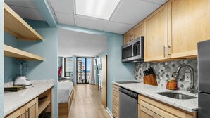 A modern kitchen with wooden cabinets, a stainless steel refrigerator, a microwave, and a dishwasher. - Lighthouse Loft at Compass Cove - Unit 1151 (Myrtle Beach)