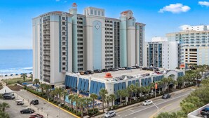 A large hotel with multiple floors, a pool area, and a view of the beach. - Lighthouse Loft at Compass Cove - Unit 1151 (Myrtle Beach)