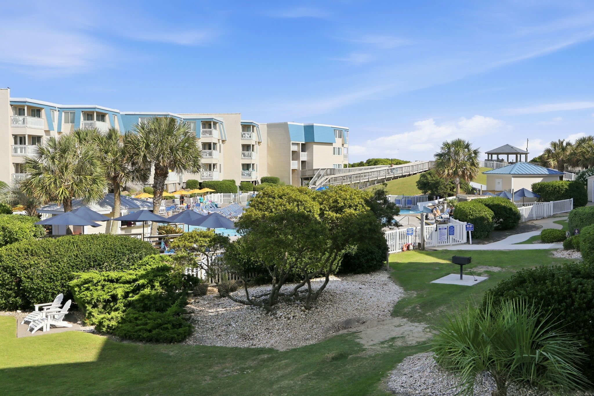 A resort with multiple-story buildings, outdoor seating, and palm trees.