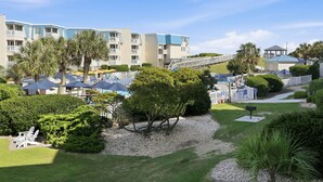 Un resort con edificios de varios pisos, mobiliario exterior y palmeras.