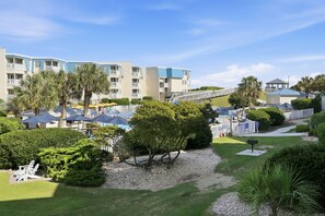Un resort con edificios de varios pisos, mobiliario exterior y palmeras.