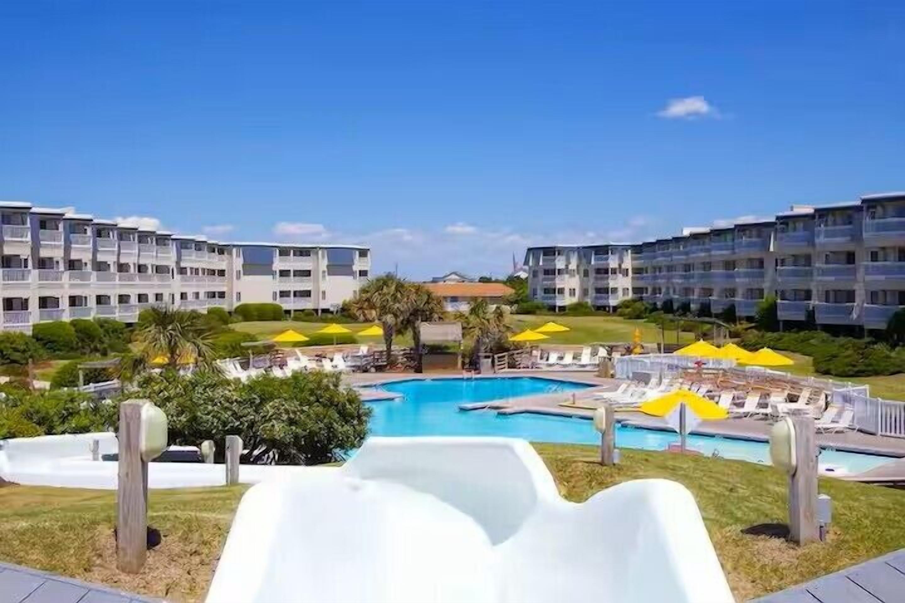 Un hotel con piscina, sedie a sdraio e ombrelloni.