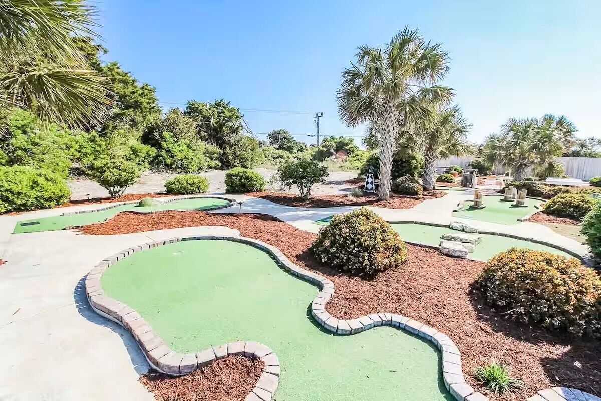 A miniature golf course with winding paths and palm trees.