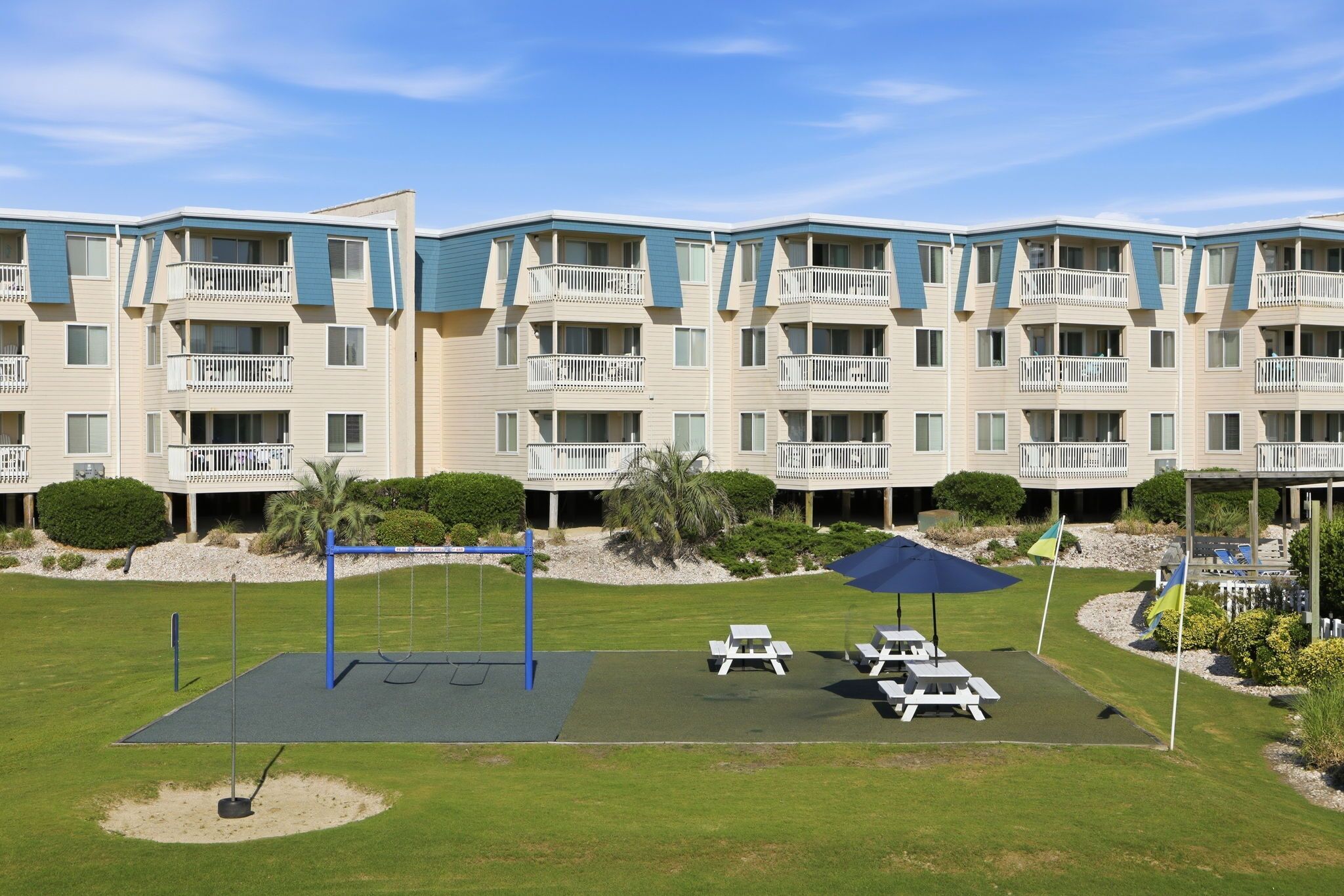 A multi-story building with balconies, a playground, and outdoor seating areas.