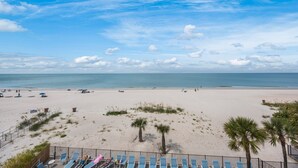 Une plage avec un rivage sablonneux, des palmiers et un ciel dégagé.