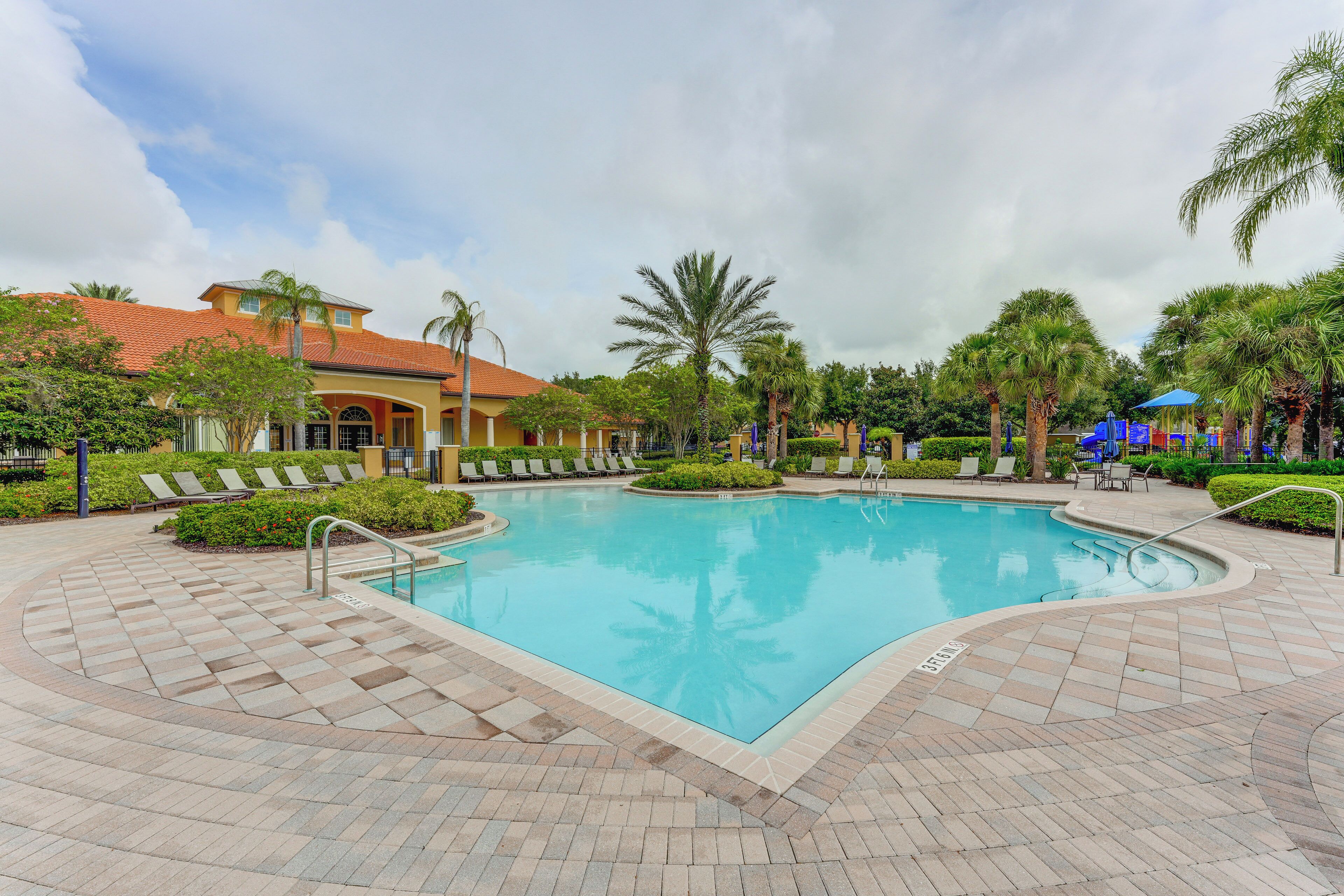 A swimming pool with lounge chairs and palm trees.