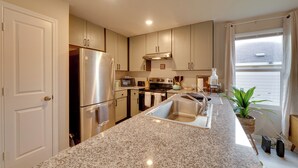 A modern kitchen with granite countertops, stainless steel appliances, and a large window providing natural light. - Easy Access to Dtwn San Antonio: Suburban Home (San Antonio)