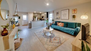 A modern living room with a sofa, coffee table, and a television. There is a kitchen in the background with cabinets and a window. - Easy Access to Dtwn San Antonio: Suburban Home (San Antonio)