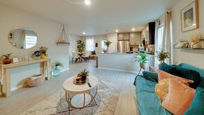 A spacious living area with a sofa, a coffee table, and a dining table. There is a kitchen in the background with modern appliances. - Easy Access to Dtwn San Antonio: Suburban Home (San Antonio)