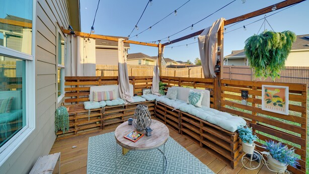 A covered outdoor seating area with wooden benches, a round table, and string lights. - Easy Access to Dtwn San Antonio: Suburban Home (San Antonio)
