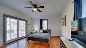 A bedroom with a bed, a ceiling fan, a TV, and a large window with curtains. - 4 Mi to Downtown! Cozy Bungalow in San Antonio (San Antonio)