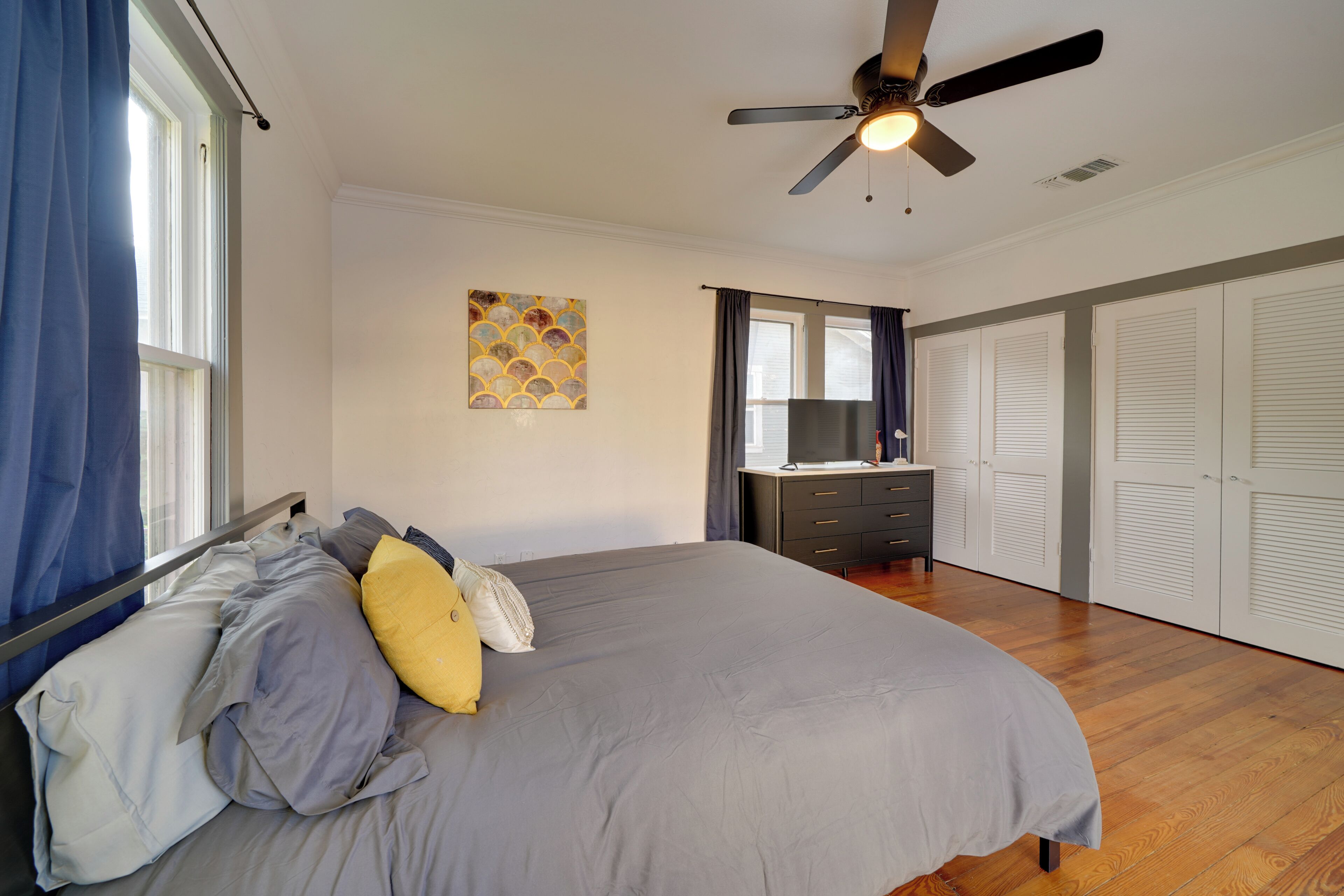 Un dormitorio con cama, ventilador de techo, cómoda y armario.