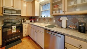 A kitchen with wooden cabinets, a stainless steel dishwasher, a microwave, and a coffee maker. - 4 Mi to Downtown! Cozy Bungalow in San Antonio (San Antonio)