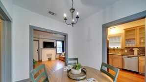 A dining area with a round table, chairs, a chandelier, and a view into the kitchen. - 4 Mi to Downtown! Cozy Bungalow in San Antonio (San Antonio)