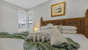Ein ordentlich bezogenes Bett mit grüner Decke, einem hölzernen Kopfteil und einem Bild an der Wand.