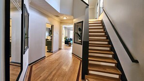 Ein modernes Interieur mit einer Holztreppe, einer Küche im Hintergrund und einem Wohnbereich.