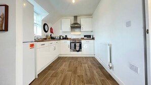 A modern kitchen with white cabinets, a wooden countertop, and a built-in oven.