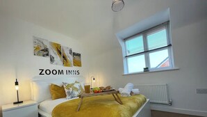 A bedroom with a bed, bedside tables, a window, and artwork on the wall.