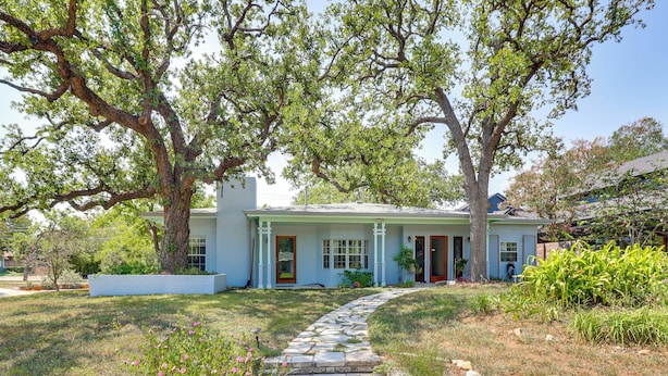 A two-story house with a stone pathway leading to the front door, surrounded by mature trees and a well-maintained lawn. - Walk to Mueller Lake Park! Home w/ Patio & Yard (Austin)