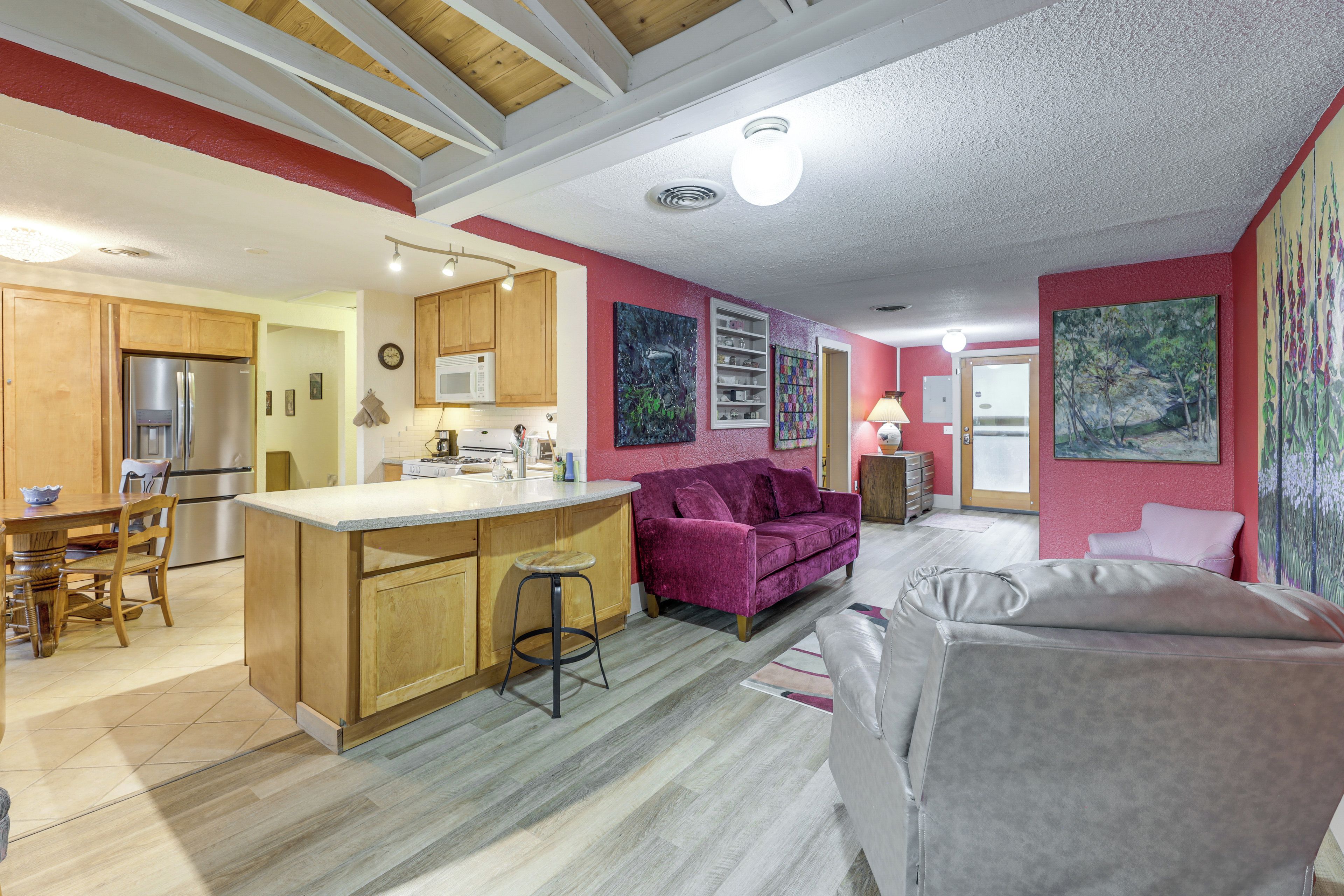 A modern kitchen with wooden cabinets, a central island, and a dining area with a table and chairs.