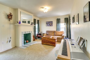 A living room with a fireplace, a sofa, a piano, and a large mirror.