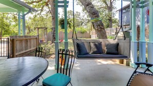A covered patio with a swing set, a table, and chairs. - Walk to Mueller Lake Park! Home w/ Patio & Yard (Austin)